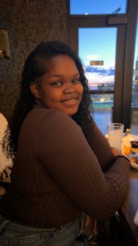 a young woman sitting at a table with a smile on her face