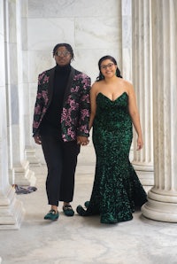 two women in green gowns standing in front of pillars